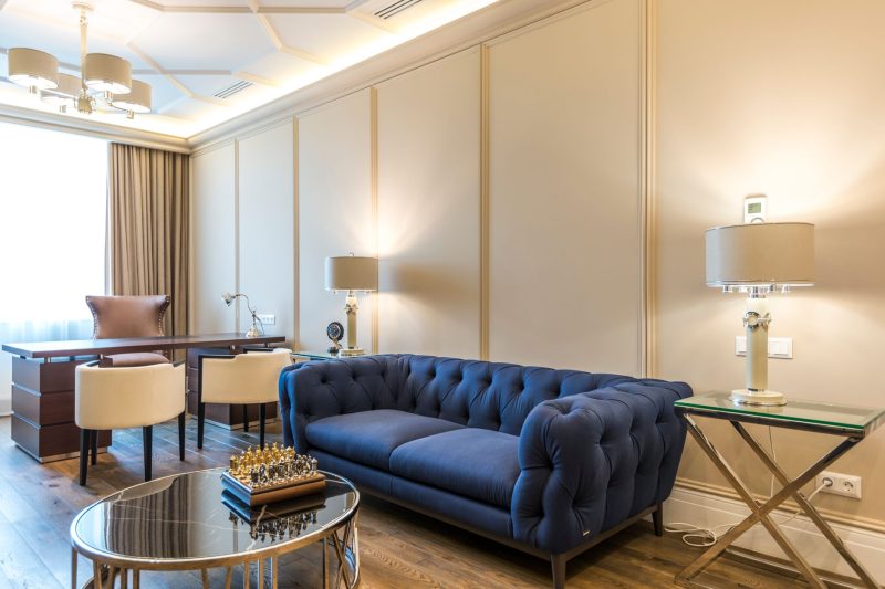 A stylish interior with modern furniture, featuring a chic blue sofa and elegant desk setup